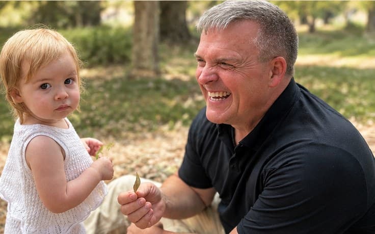 Robert Upton smiling with a young child outdoors